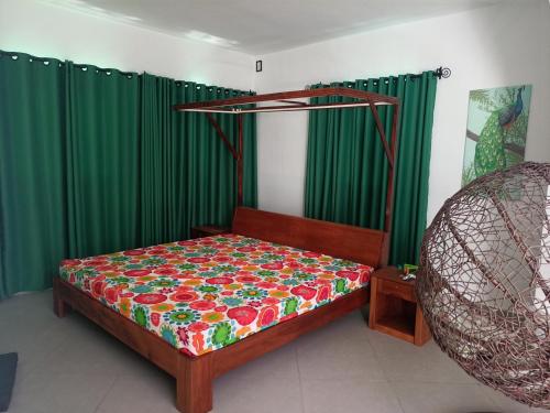 a bedroom with a bed and green curtains at Villa sakinu in Mahajanga
