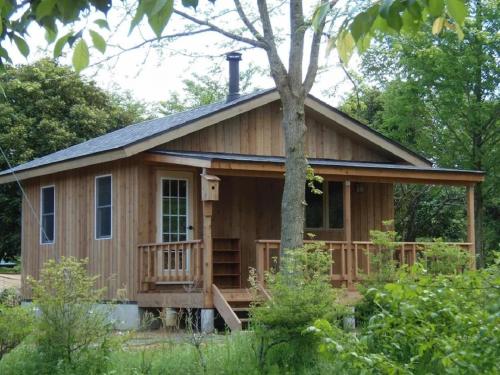 a wooden cabin with a porch and a tree at Eleven Auto Camp Park - Vacation STAY 44750v in Kururi