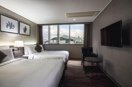 釜山にあるケントホテル 広安里 バイ ケンジントンのベッド2台と窓が備わるホテルルームです。