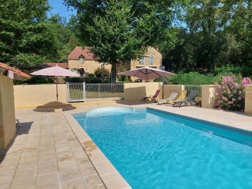 une piscine avec chaises et parasols dans une cour dans l'établissement Domaine du Bois Noir, à Milhac
