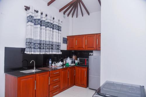 a kitchen with wooden cabinets and a sink and a refrigerator at Villa A.SMS in Induruwa
