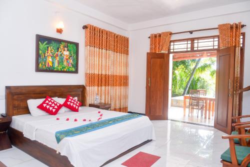 a bedroom with a bed with red pillows on it at Villa A.SMS in Induruwa