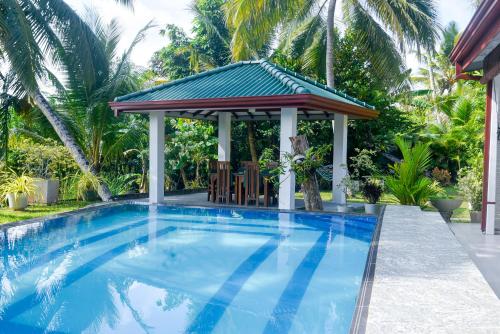 a swimming pool with a gazebo at Villa A.SMS in Induruwa