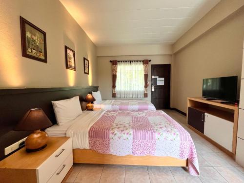a bedroom with a large bed and a television at Rommai Greenpark in Lampang