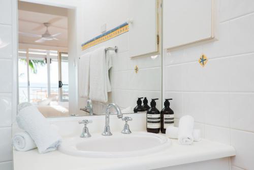 a white bathroom with a sink and a mirror at Wategos Villa in Byron Bay