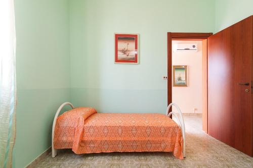 トッレ・サン・ジョヴァンニ・ウジェントにあるThe Green Sea Small Houseのベッド1台(オレンジの毛布付)が備わる客室です。
