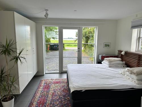 a bedroom with a large bed and a sliding glass door at Langø Feriecenter - Sea View in Langø