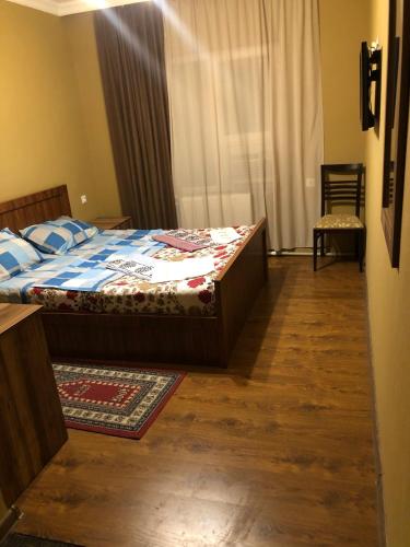 a bedroom with a bed with a wooden floor and a window at Hotel Nikea Paradiso in Kutaisi