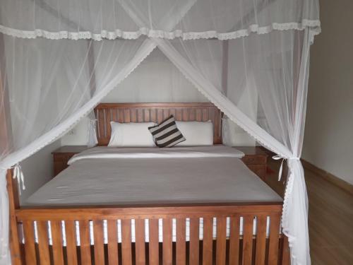 a bedroom with a canopy bed with white curtains at Divine View Homestay in Ella