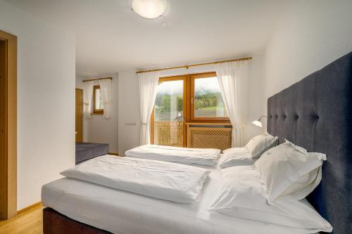 a bedroom with two beds with white sheets and a window at Ferienwohnung Mair am Bach in Brunico