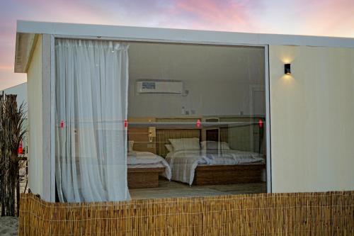 Blick auf ein Schlafzimmer durch eine Glasschiebetür in der Unterkunft Al-Rahal Desert Camp in Mesaieed