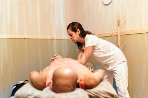 a woman is performing acupuncture on a mans back at Alaya Poleg in Netanya