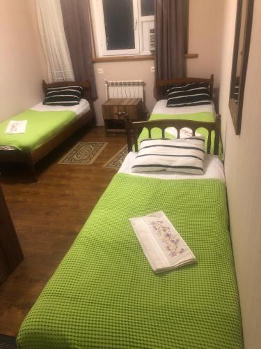 two beds in a room with green sheets at Hotel Nikea Paradiso in Kutaisi