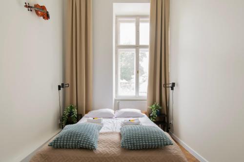 1 dormitorio con 1 cama con 2 almohadas y ventana en Apartments Studencka Street, Next to Planty Park en Cracovia