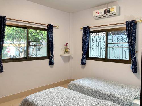 a bedroom with two beds and two windows at THAIGO Comfort Stay - Private House in Central Kanchanaburi in Kanchanaburi City
