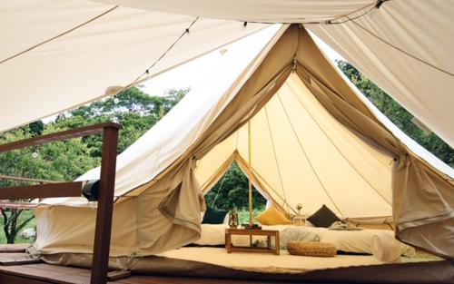 ties Camp Ground Nagiso في ناغيسو: خيمة بيضاء كبيرة بها سرير وطاولة