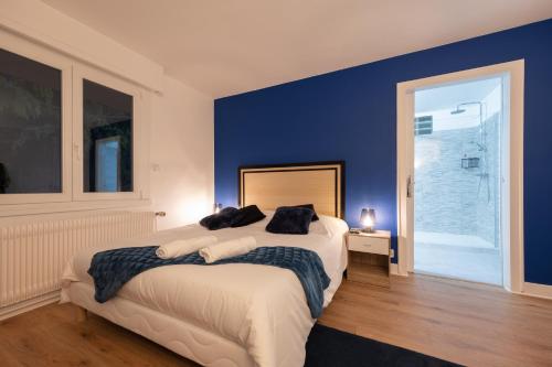 a bedroom with a large bed with a blue wall at Gîte Villa La Chèvrerie centre in Épinal