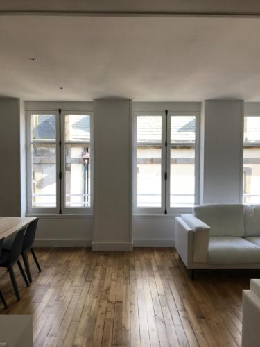 a living room with a couch and a table and windows at Appartement de charme in Saint Malo