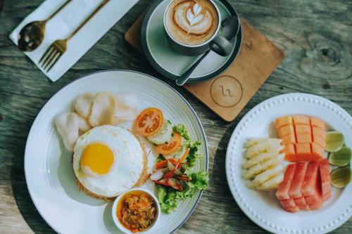 una mesa con dos platos de desayuno y una taza de café en Lovinalife Room & Cafe, en Lovina