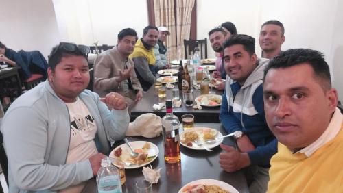 Un gruppo di uomini seduti intorno a un tavolo che mangiano cibo di Hotel Admire Pokhara Pvt. Ltd. a Pokhara