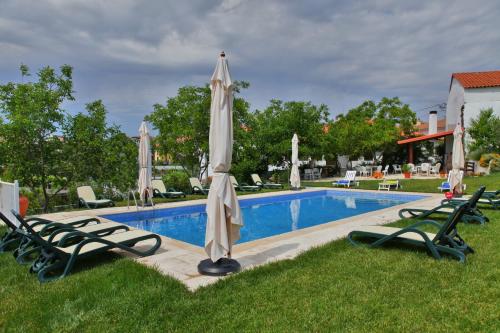 a pool with two lawn chairs and an umbrella at Casa do Médico in Carção