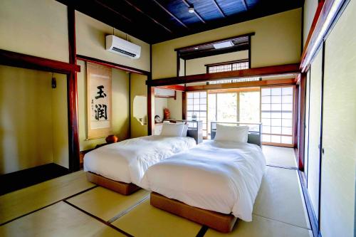 a bedroom with two beds in a room at 佐渡古民家ステイ さどまり -Sadomari Historical Villa- in Sado
