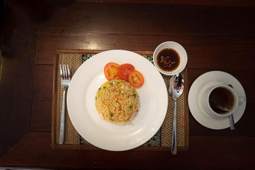 a plate of food with tomatoes and a cup of coffee at Nawin Palace Guesthouse in Phnom Penh