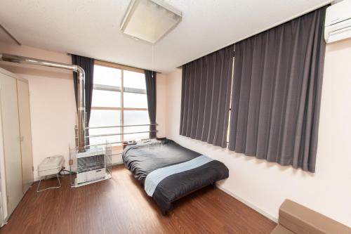 Big Stone Tsukuda 41平米 R303 في أوموري: غرفة نوم بسرير ونافذة كبيرة