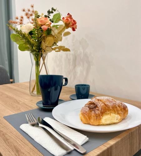 een tafel met een bord gebak en een vaas met bloemen bij Chiaia Exclusive Apartment in Napels