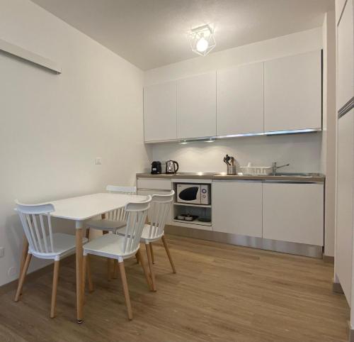 cocina con armarios blancos, mesa y sillas en Basiglio - Residenza Sorgente, en Basiglio