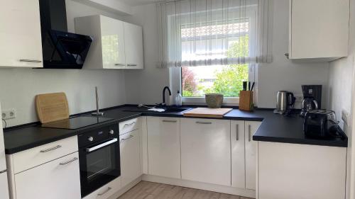 a kitchen with white cabinets and a black counter top at Ferienwohnung Lilienthal in Lilienthal