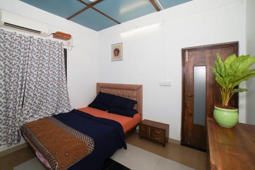 a bedroom with a bed and a plant in it at 6Tamarind in Gholvad