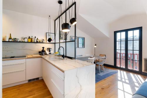 une cuisine avec des armoires blanches et un comptoir dans l'établissement Appartement avec vue sur la côte des Basques By Ginto Hotels, à Biarritz