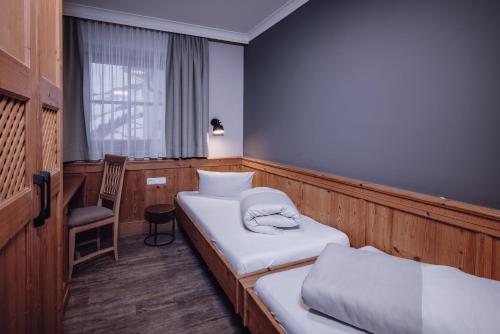 a room with two beds and a chair and a window at Familienresort Ellmauhof - das echte All Inclusive in Saalbach Hinterglemm
