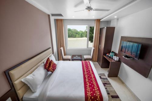a hotel room with a bed and a window at Hotel Trimurti in Haridwār