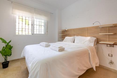 um quarto com uma grande cama branca com toalhas em 8 Apartment with two poolareas, two terraces & free padel Manilva Duquesa em San Luis de Sabinillas