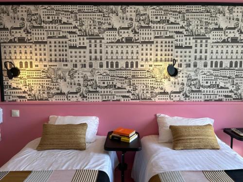 two beds in a room with a mural of buildings at Hôtel de la Croix-Rousse in Lyon