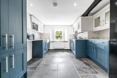 a large kitchen with blue cabinets and a window at Knott House Farm in Keswick