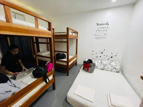 een kamer met 2 stapelbedden en een persoon met een laptop bij La Casa Dania Backpackers Hostel in Panglao