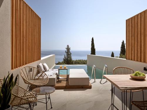 een patio met een tafel en stoelen en de oceaan bij The Sall Suites - Complex B in Agios Nikolaos