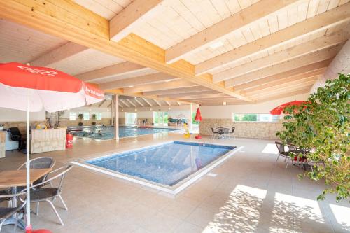 an indoor swimming pool with a table and an umbrella at Camping Marvilla Parks Friese Meren - Roan in Wijckel