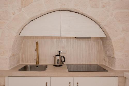 eine Küche mit einer Spüle und einer weißen Haube in der Unterkunft Trullo Cinquenoci Suite in Locorotondo