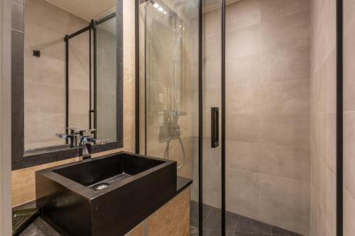 La salle de bains est pourvue d'un lavabo noir et d'une douche. dans l'établissement Luxury apartment - 5 min walk from Champs-Elysées, à Paris
