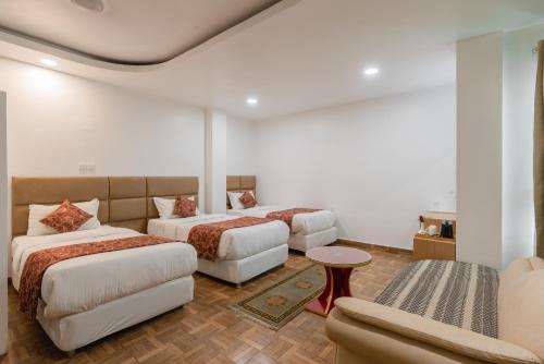 a hotel room with two beds and a couch at Hotel Ratnasambhava in Lumbini