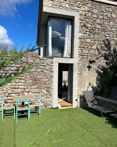 a building with a window and a bench in a yard at Maisonnette jardin jacuzzi au cœur de Chambles in Chambles