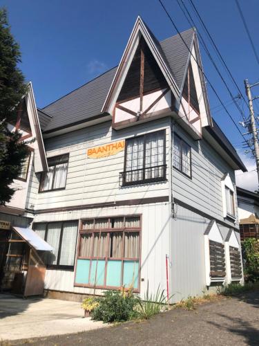 un gran edificio blanco con techo negro en 貸別荘バーンタイ戸狩 en Togari