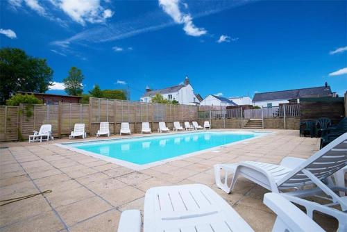 a swimming pool with lounge chairs and a fence at Meadow Lakes Holiday Park in Grampound