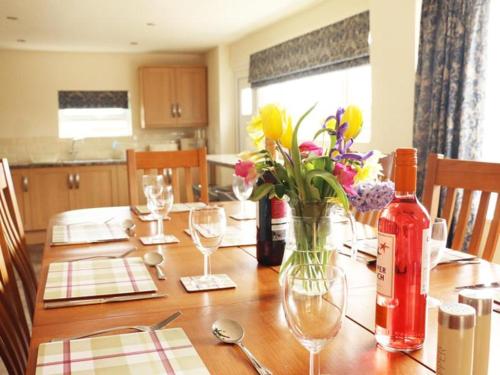 a wooden table with flowers in a vase on it at Meadow Lakes Holiday Park in Grampound