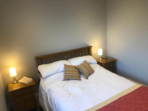 a bedroom with a white bed with two lamps at Bruíon Connemara in Cleggan