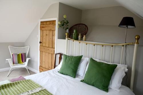 a bedroom with a bed with green and white pillows at Spring Cottage,Gorgeous and Hi-spec in Kilkhampton